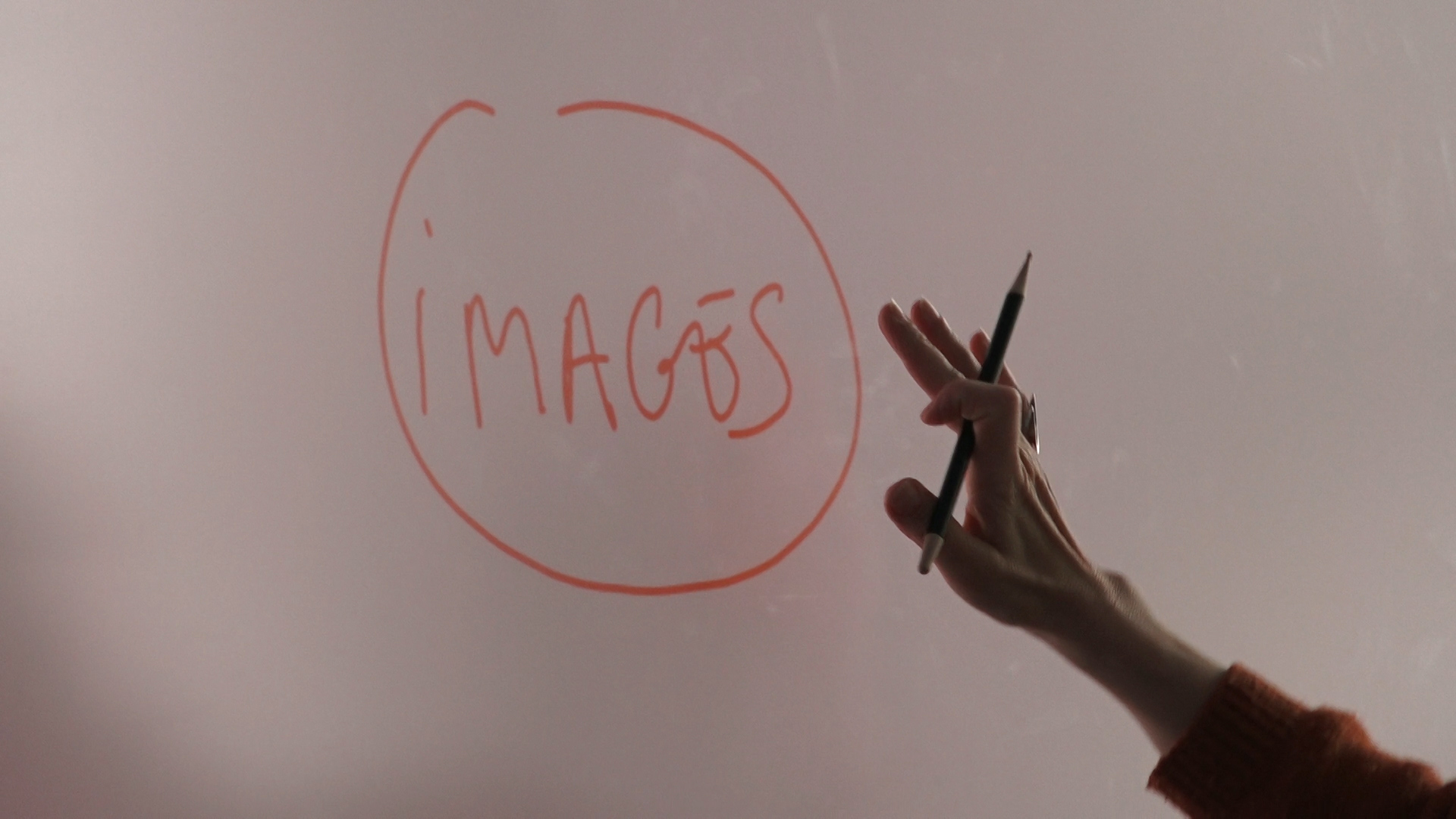 Sur un tableau blanc il est écrit : images. Une main se tend vers le mot.