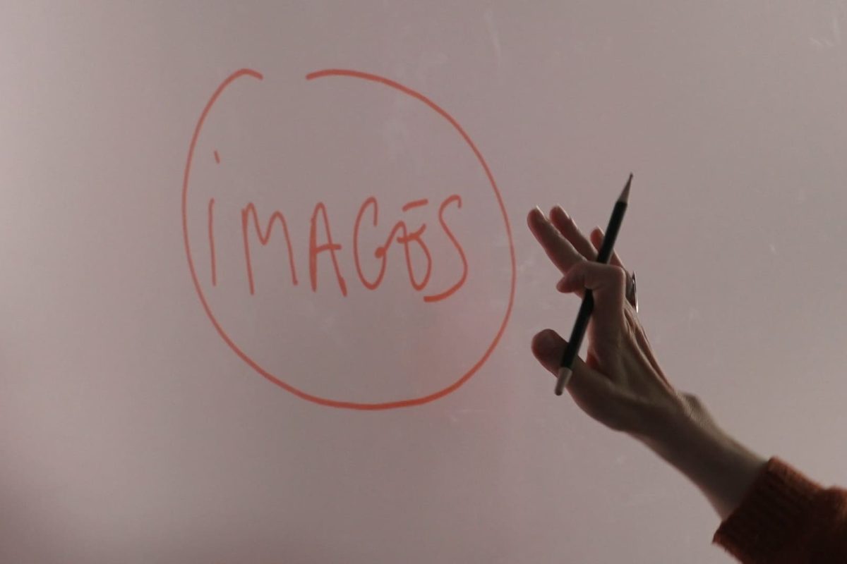 Sur un tableau blanc il est écrit "images" en rouge. Une main tenant un stylo se tend vers le mot.
